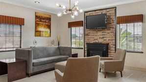 A living room with a sofa, armchairs, a flat-screen TV, a fireplace, and a chandelier. - Quality Inn & Suites Beaumont (Beaumont)