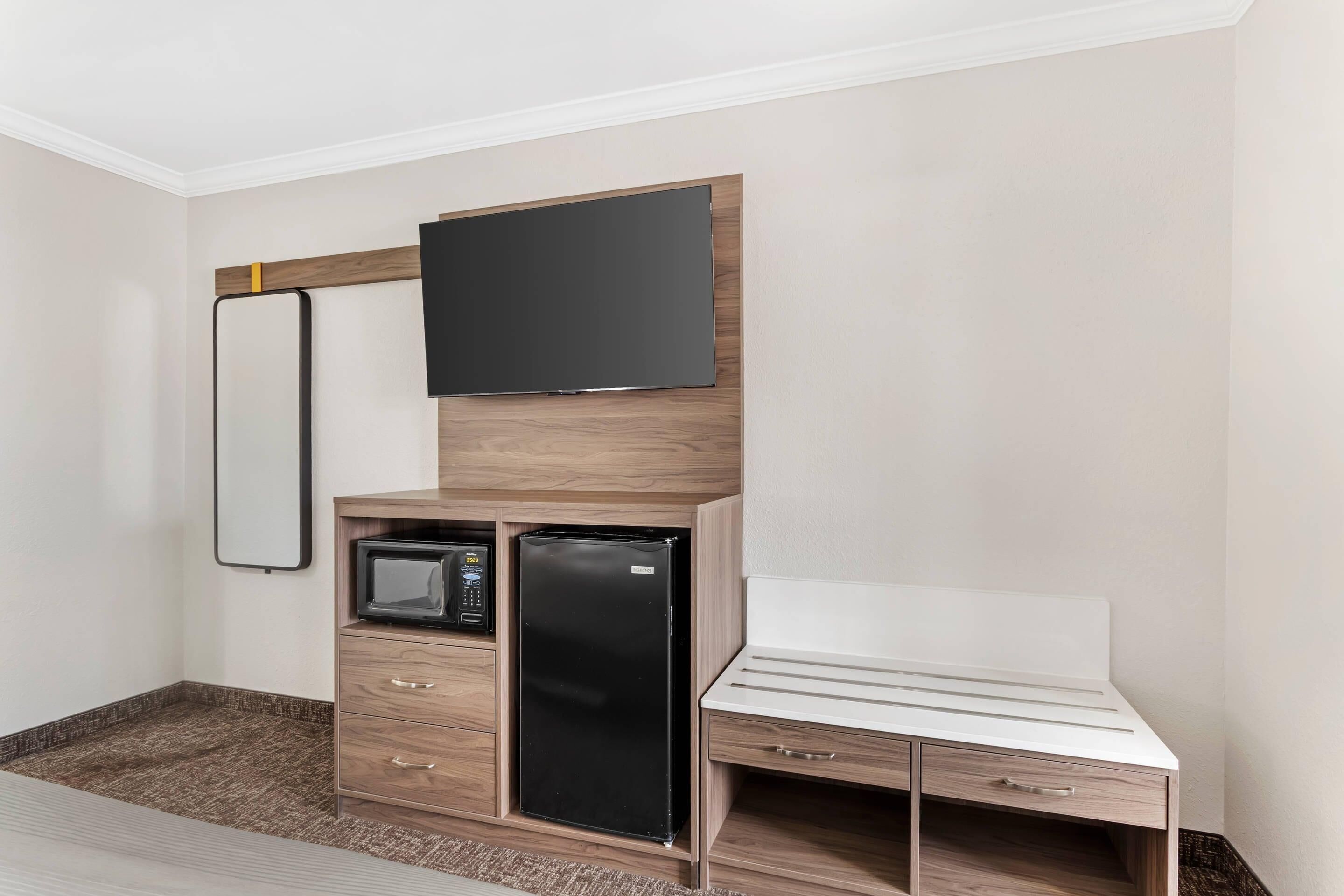 A compact room with a built-in TV, a microwave, and a refrigerator.