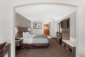 A hotel room with a bed, bedside table, lamp, and a TV. - Quality Inn & Suites Beaumont (Beaumont)