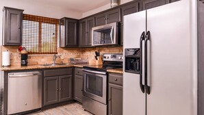 A kitchen with dark cabinets, stainless steel appliances, a microwave, oven, dishwasher, and a water dispenser. - Quality Inn & Suites Beaumont (Beaumont)