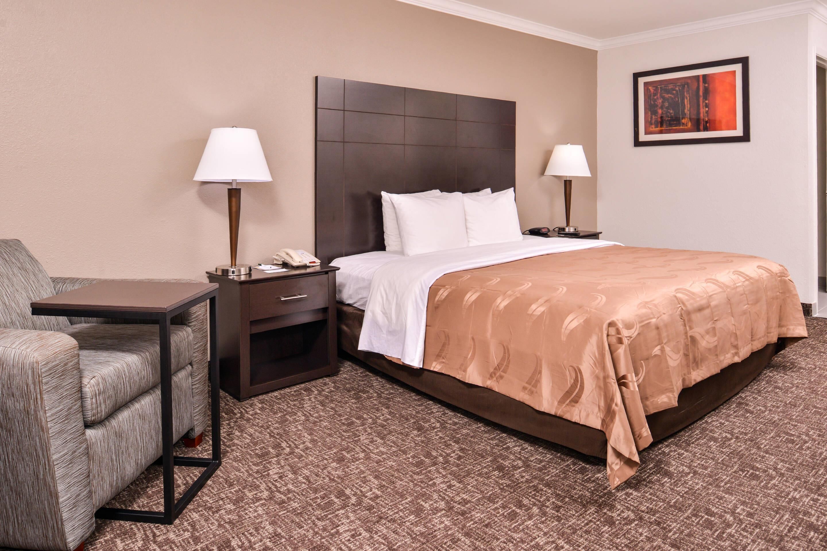A hotel room with a bed, two bedside tables, a chair, and a nightstand.