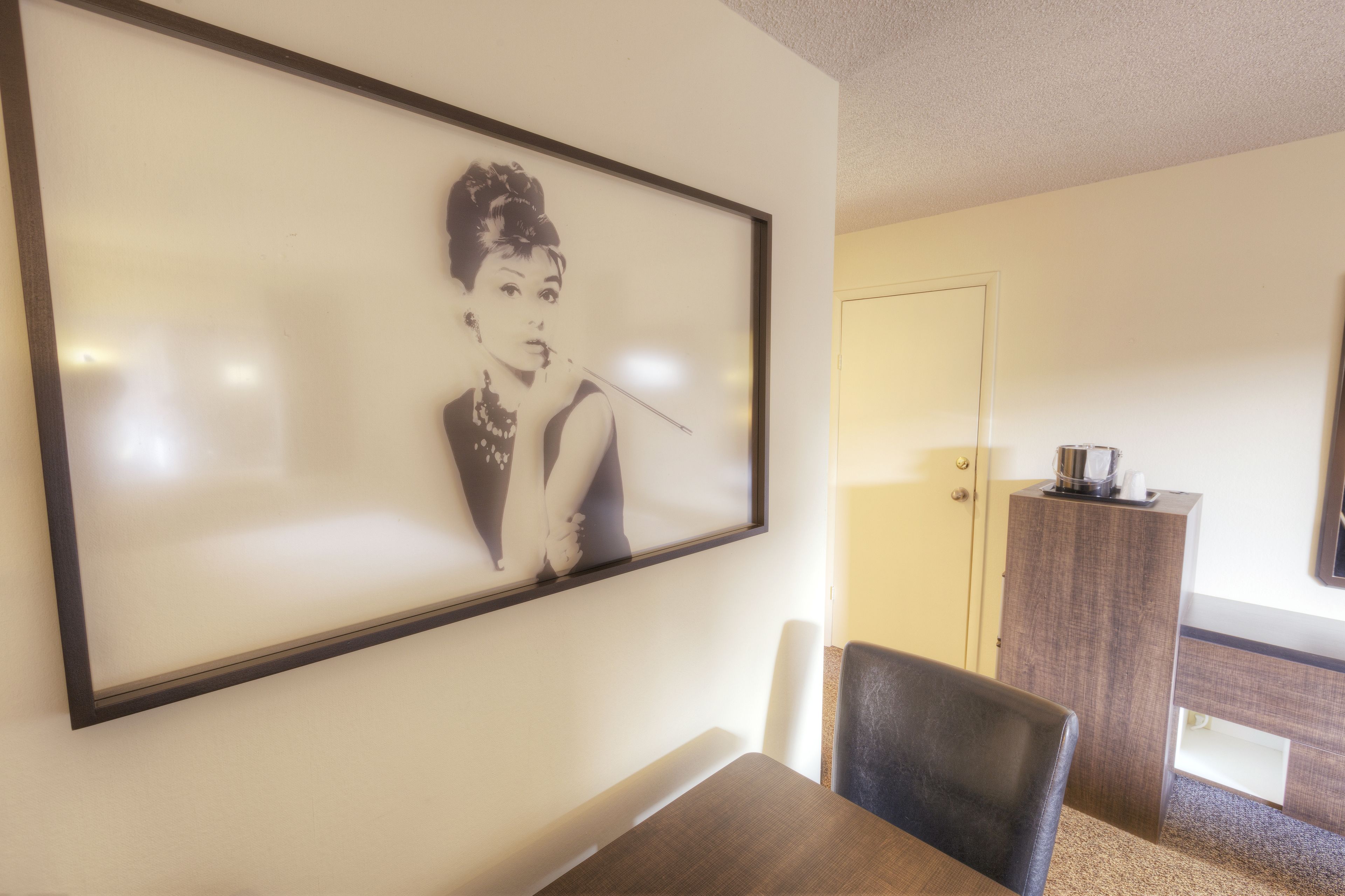 Ein gerahmtes Schwarz-Weiß-Foto an der Wand, ein Holzesstisch und ein dunkel gefärbter Stuhl.