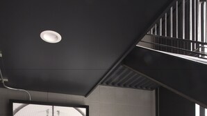 Un intérieur moderne avec une grande œuvre d’art encadrée représentant une danseuse, un escalier et un luminaire au plafond.