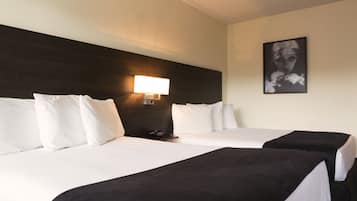 A hotel room with two beds, white bedding, a dark headboard, a bedside lamp, and a framed picture on the wall.