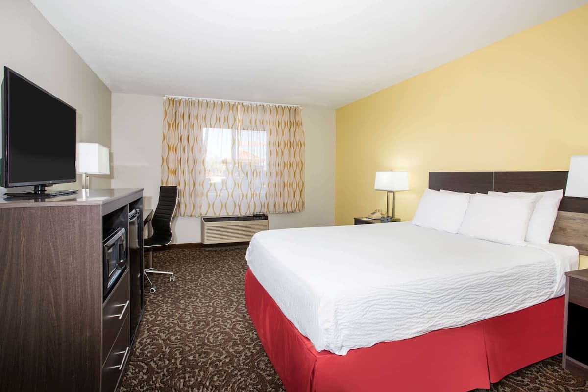 Ein Hotelzimmer mit Bett, Fernseher, Schreibtisch und Stuhl.