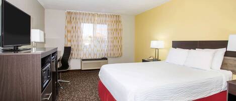 A hotel room with a bed, a TV, a desk, and a chair.