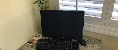 Una computadora de escritorio con teclado y monitor sobre una encimera de granito.