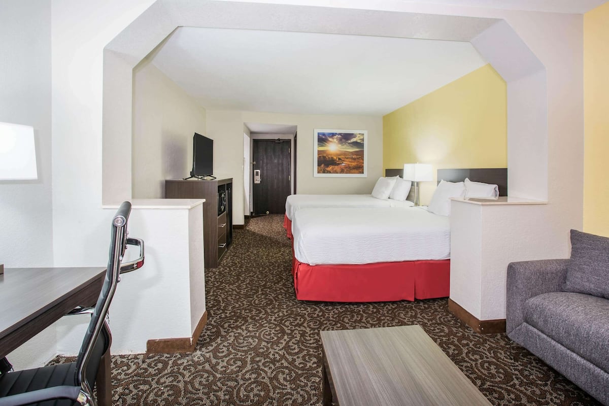 Ein Hotelzimmer mit Bett, Sofa, Schreibtisch und Fernseher.