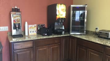 A kitchen with a coffee machine, a toaster, and a refrigerator.