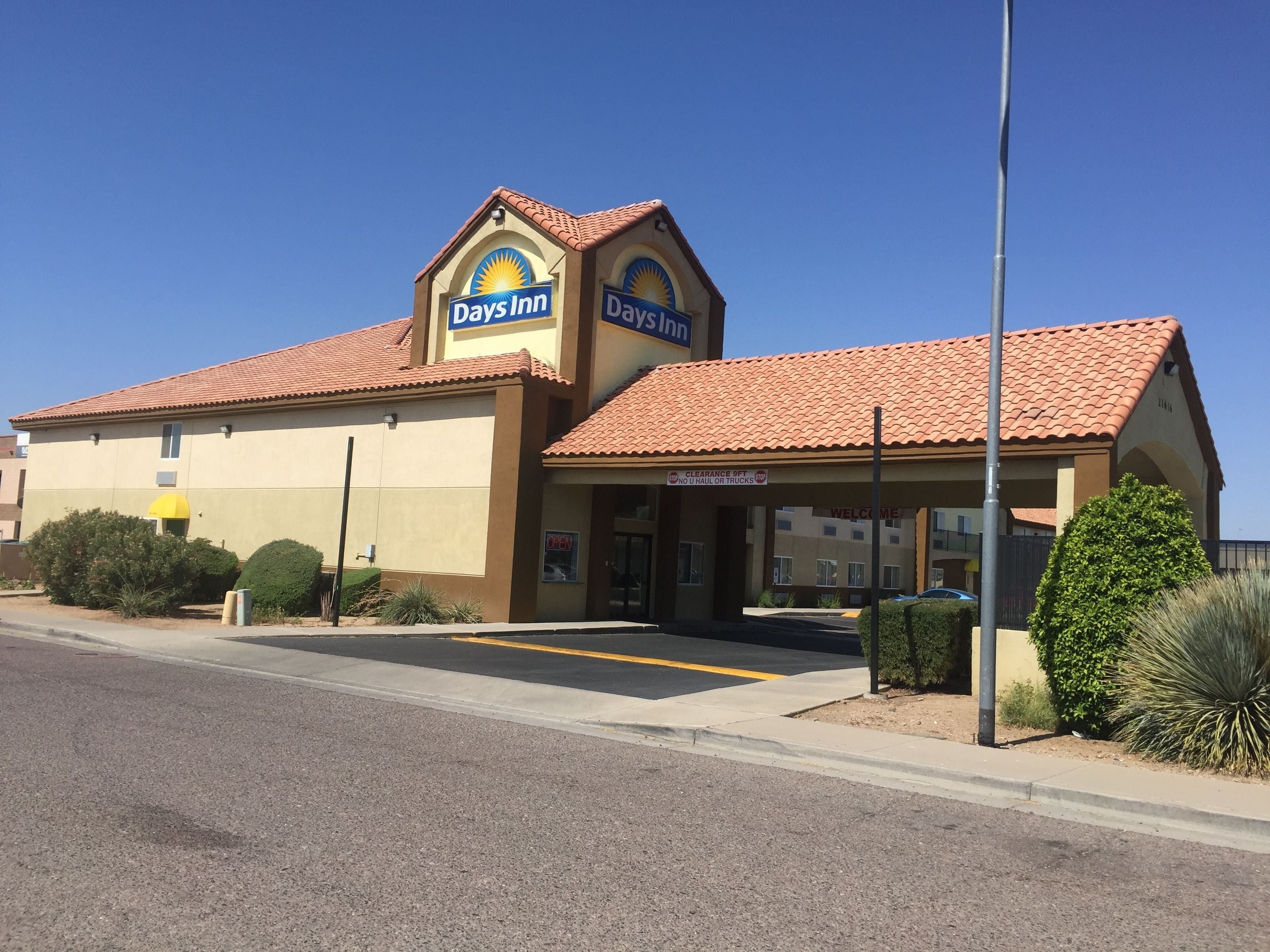 A Days Inn with a clear entrance, a sign indicating no U-Haul or trucks allowed, and a clear sky above.