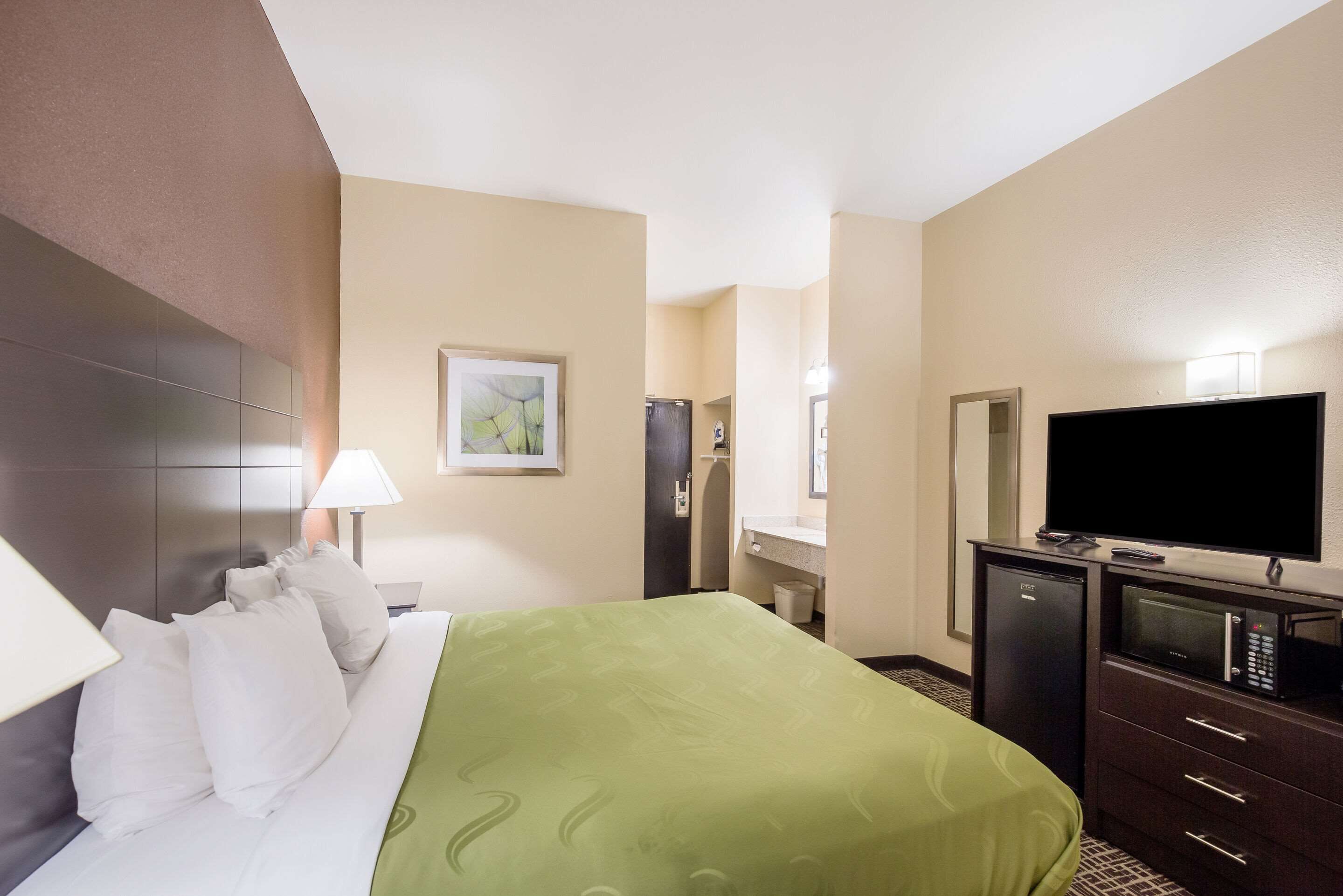 Une chambre d’hôtel équipée d’un lit, d’une télévision, d’un bureau et d’un miroir.
