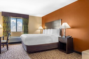A hotel room with a bed, bedside lamps, a desk, and a chair. - Quality Inn & Suites Caseyville - St. Louis (Caseyville)
