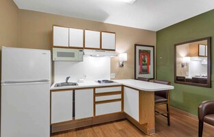 Una cocina compacta con refrigerador, microondas y lavamanos.