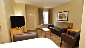 A hotel room with a bed, a TV on a wooden stand, a sofa, a small table, and a window with curtains. - Extended Stay America Suites Nashville Airport Music City (Nashville)