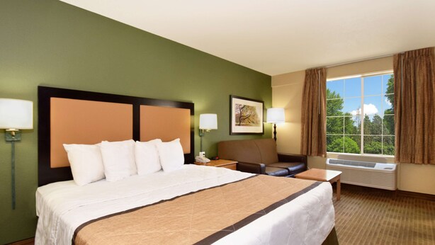 A hotel room with a large bed, a desk, a chair, a window with curtains, and a picture on the wall. - Extended Stay America Suites Nashville Airport Music City (Nashville)