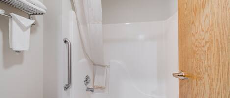 Un baño con bañera, cortina de ducha, toallero y puerta de madera.