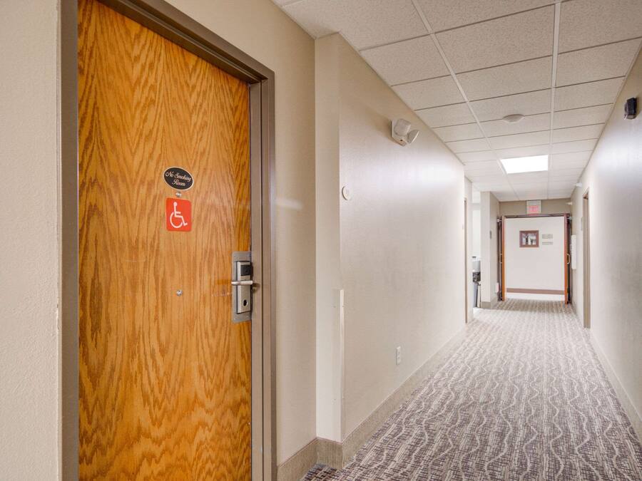 A hotel hallway with a wooden door marked "Smoking Room" and a wheelchair accessibility sign.