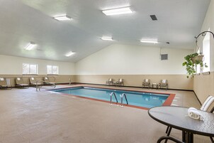 A large indoor swimming pool with multiple lounge chairs and a table.