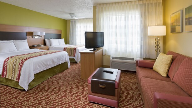 Een hotelkamer met twee bedden, een televisie, een bureau, een bank en een lamp.