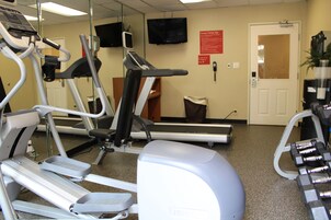 Un gimnasio equipado con cintas de correr, elípticas y pesas sueltas.