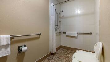 Un baño pequeño con azulejos, una ducha, un inodoro y un pasamanos.