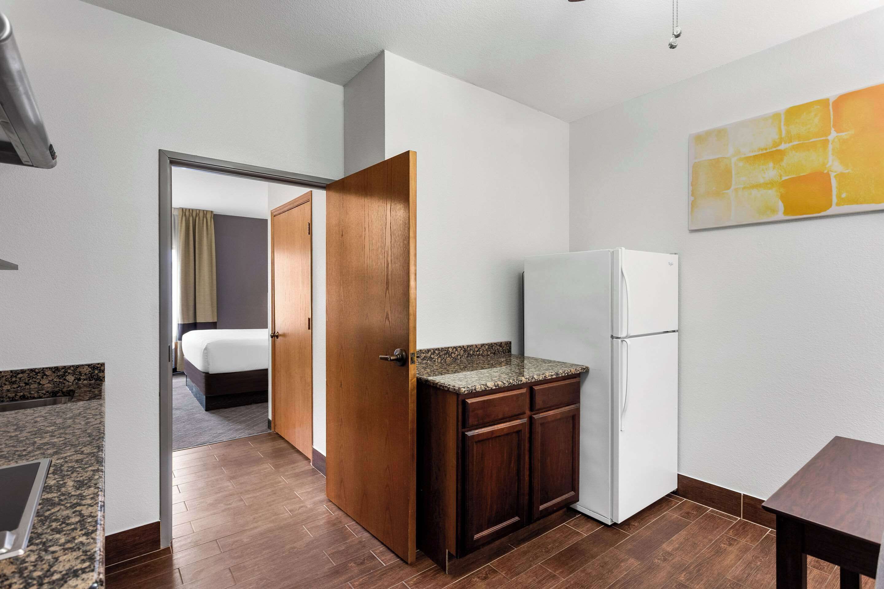 A compact hotel room with a kitchenette, a bed, and a bathroom visible through an open door.
