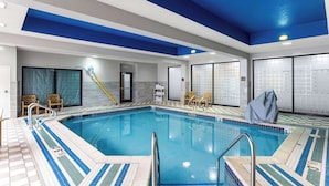 Una piscina interior con carriles claramente marcados, suelo de baldosas azules y blancas, y techo con rayas azules y blancas.