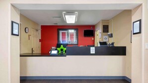 A reception area with a counter, a clock, a television, and a window. - Southpoint Suites Jacksonville (Jacksonville)