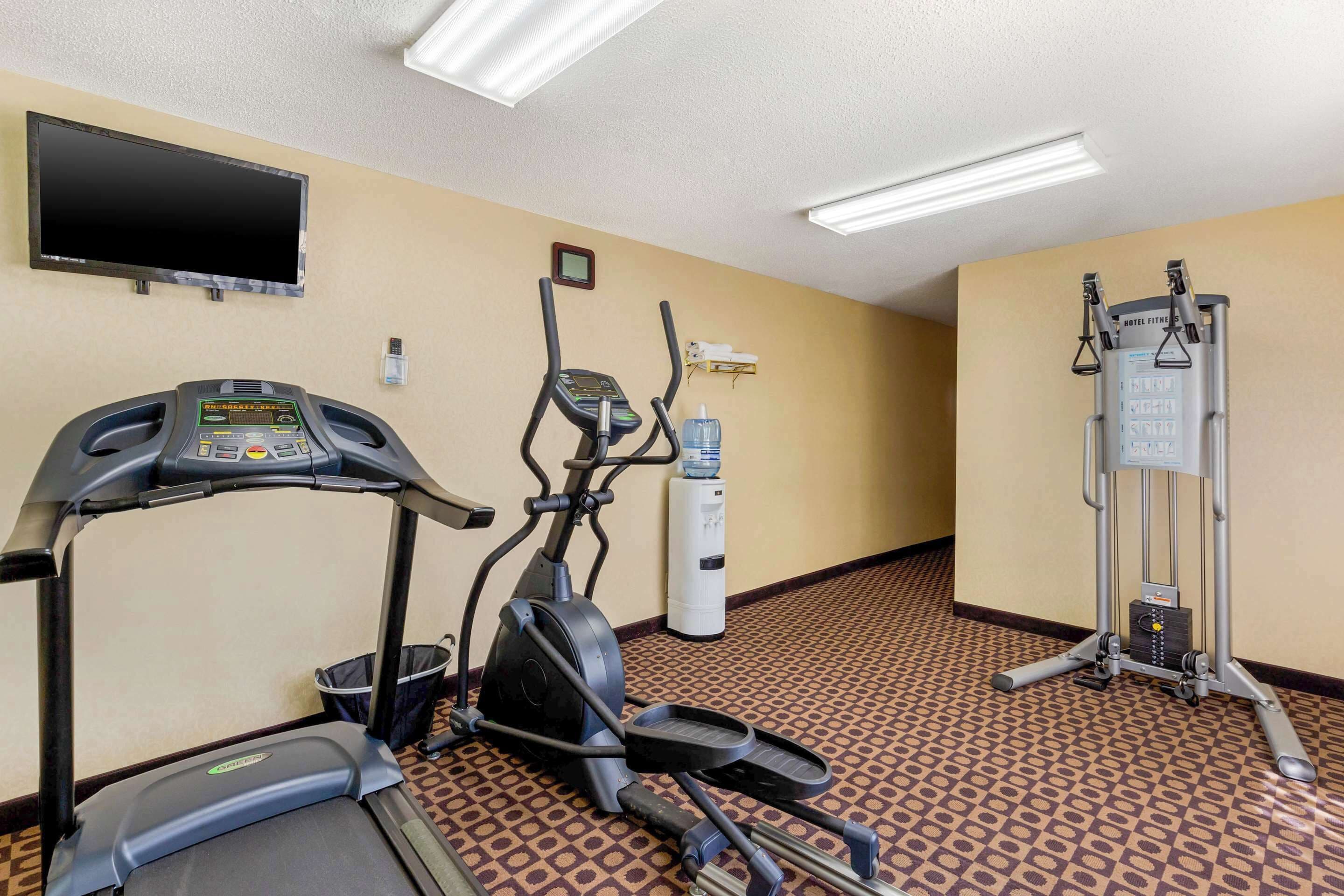 A fitness room with a treadmill, elliptical, and weight machine.