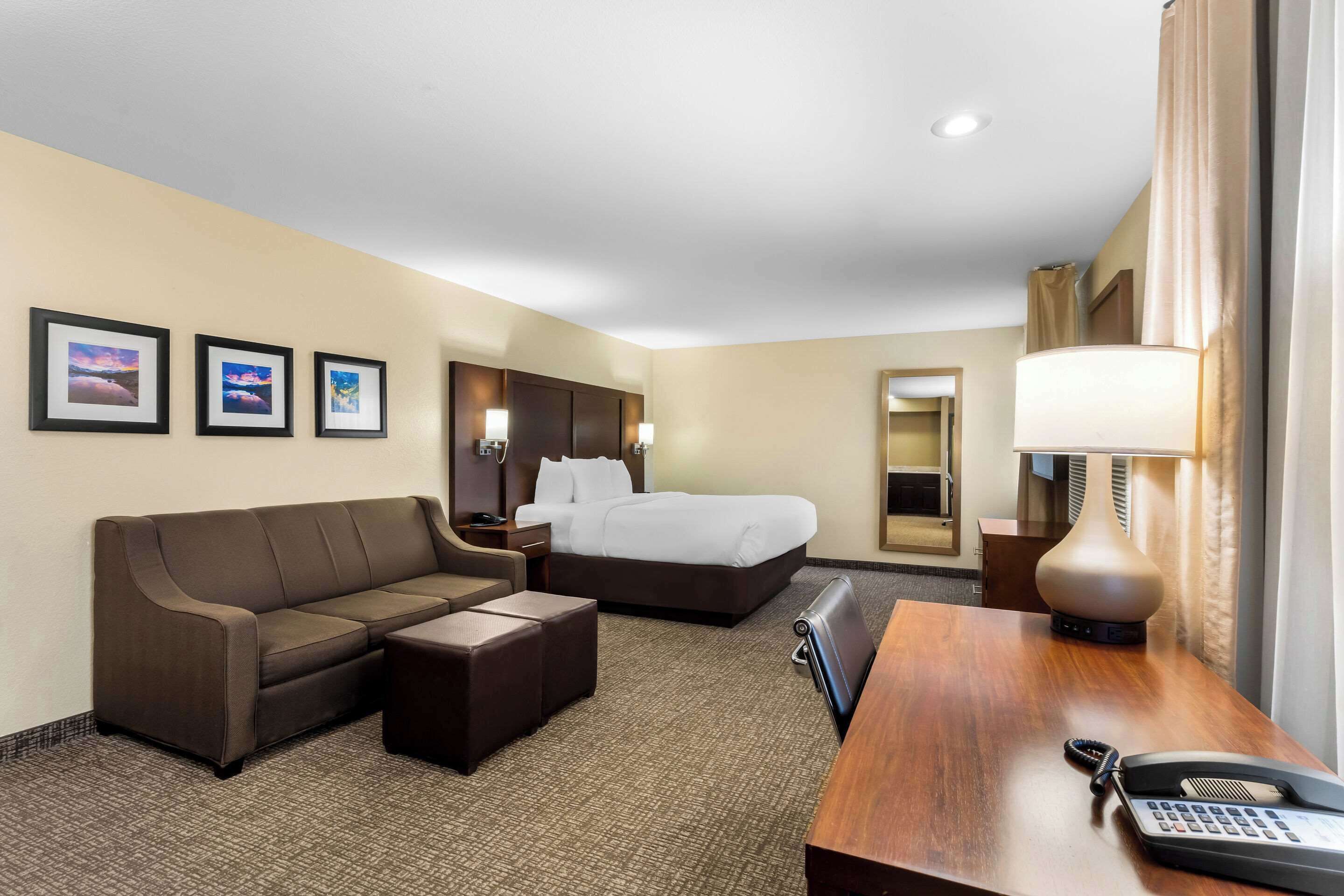 Ein Hotelzimmer mit Bett, Sofa, Schreibtisch und Lampe.