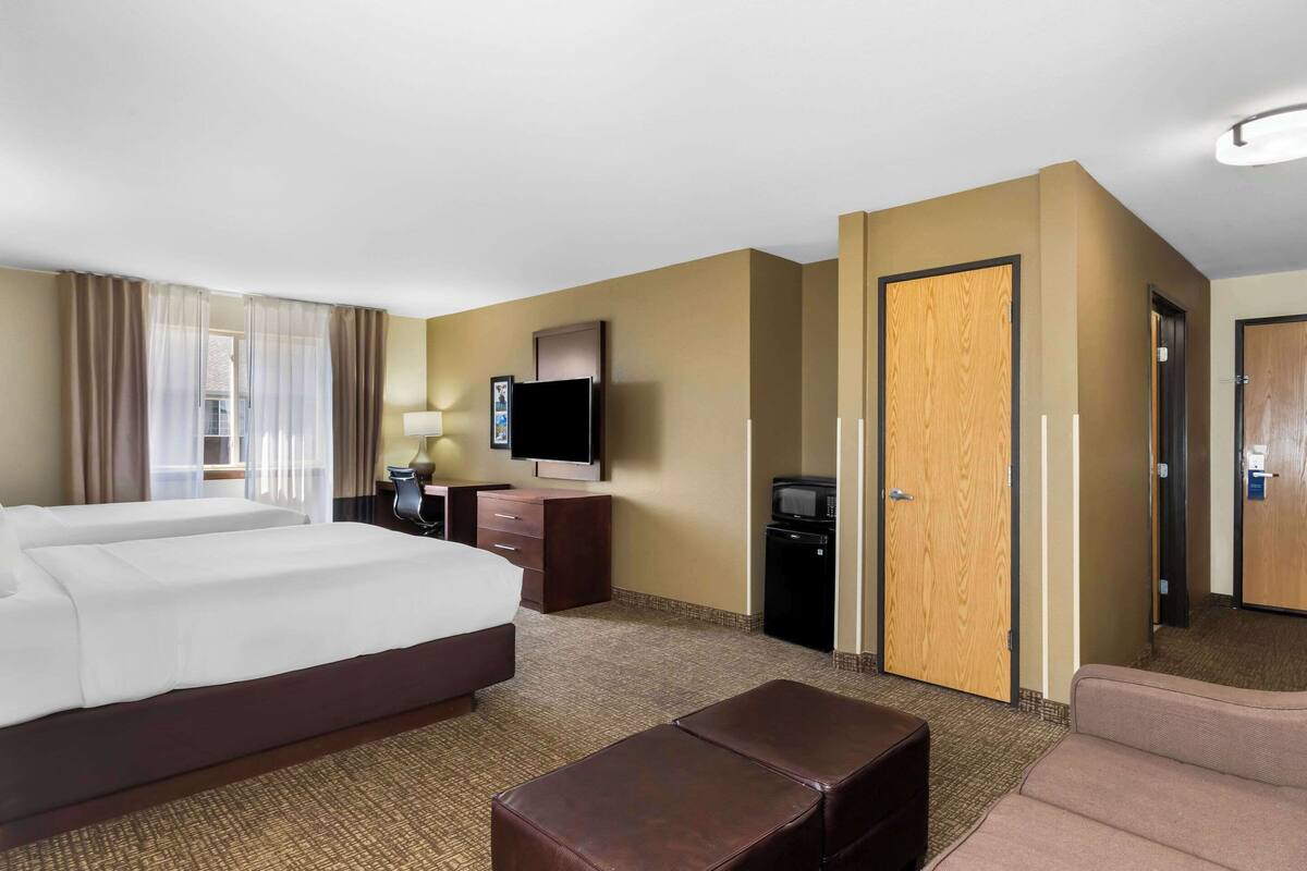 A hotel room with a large bed, a desk with a computer, a television, and a microwave.