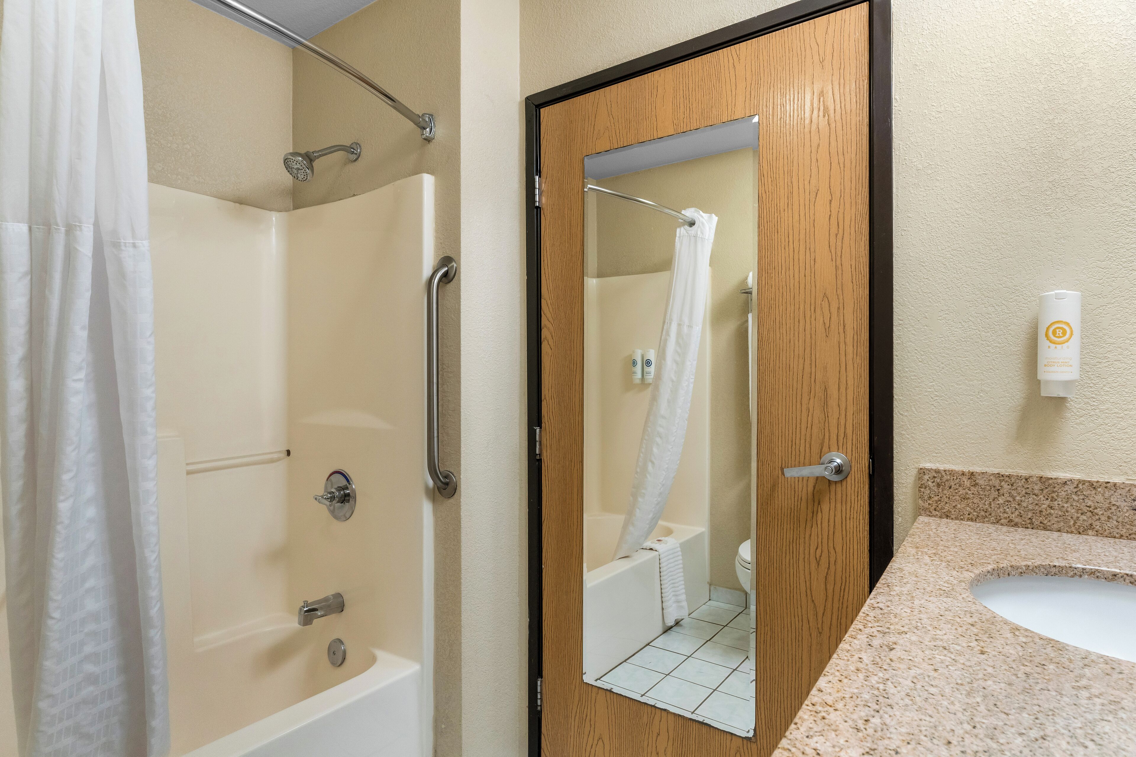A bathroom with a shower, a sink, and a mirror.