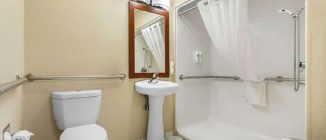 Un baño con inodoro, lavamanos y ducha a ras de suelo.