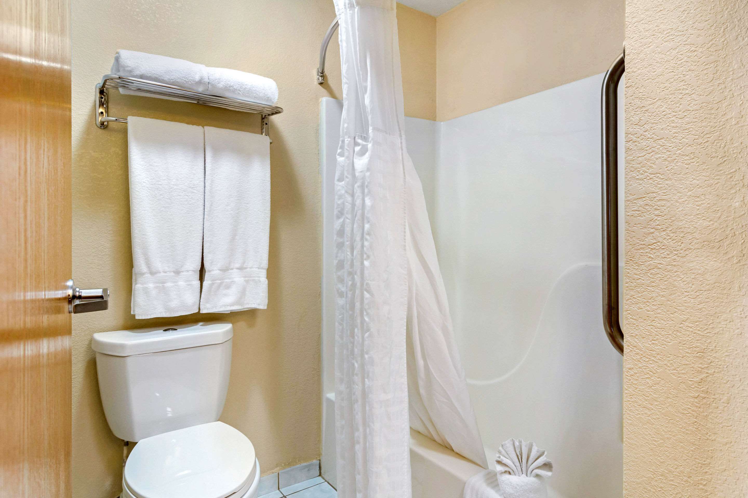 A bathroom with a toilet, a shower with a curtain, and two towels hanging on a rack.