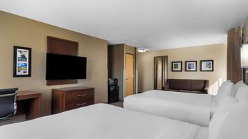 A hotel room with two beds, a TV, a desk, and a minibar.