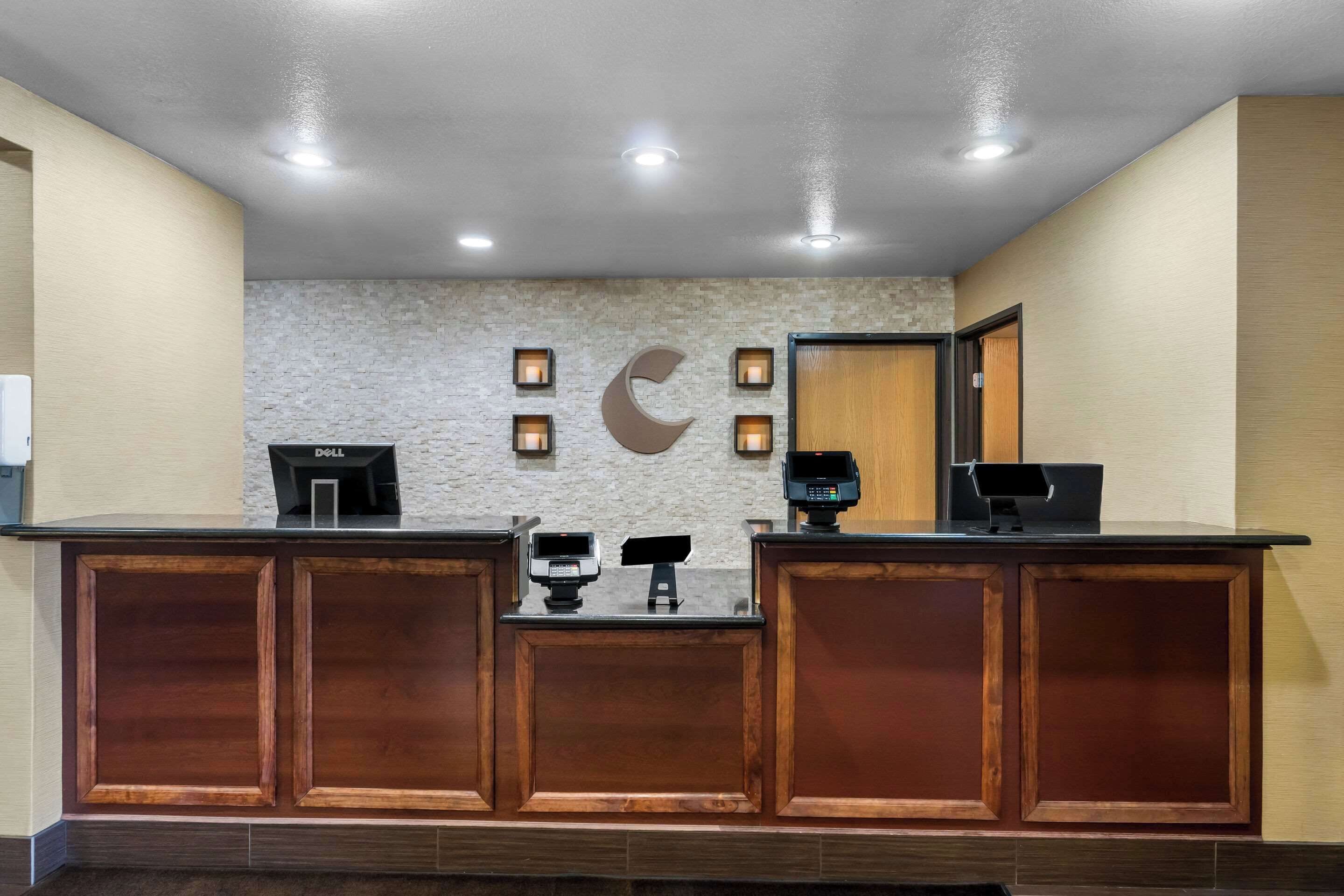 Una recepción con un fondo de pared de piedra, una gran decoración en forma de luna creciente y una computadora Dell.