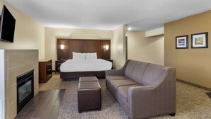 Ein Hotelzimmer mit Bett, Sofa, Kamin und Teppichboden.