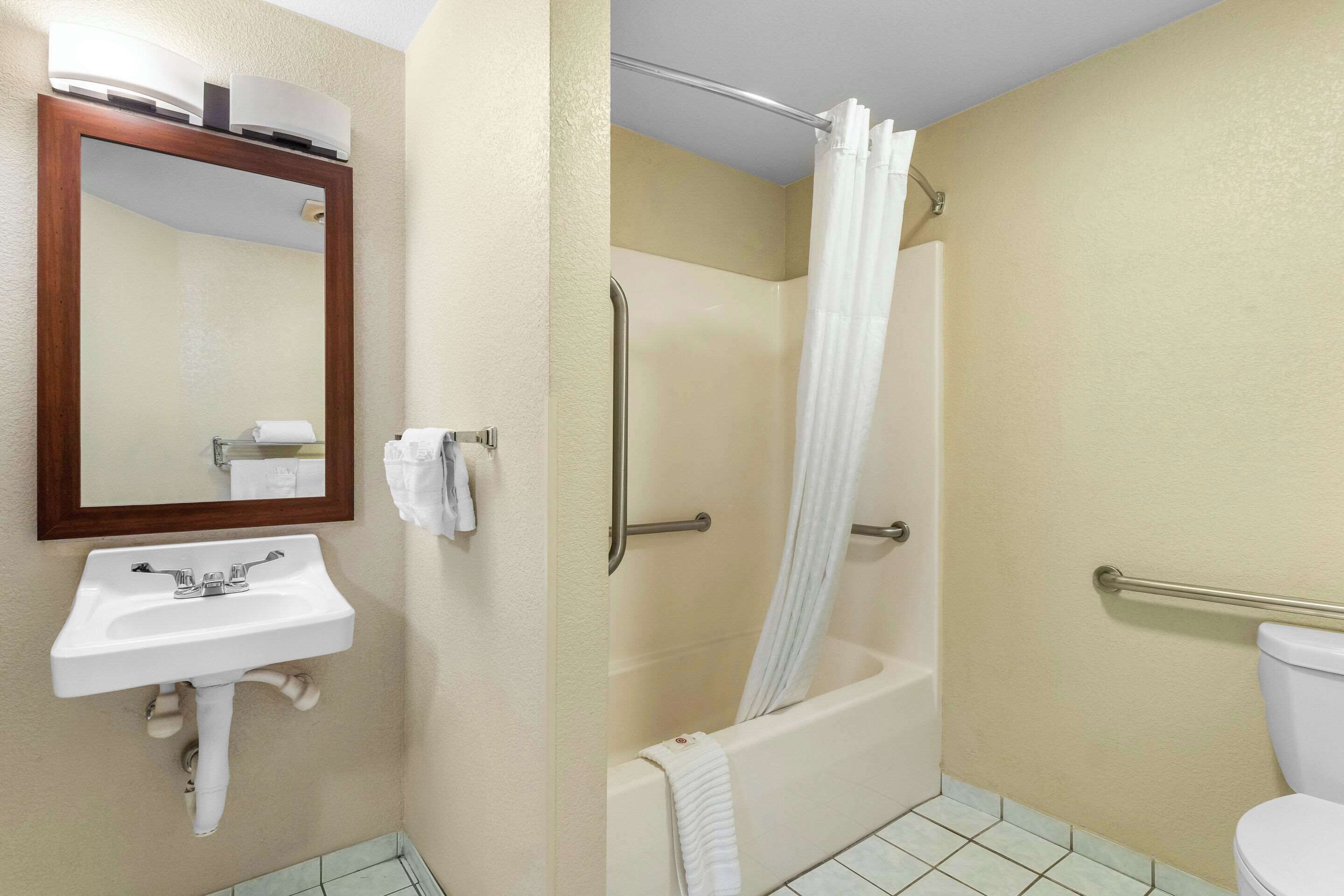 Un baño con lavamanos, espejo, ducha e inodoro.