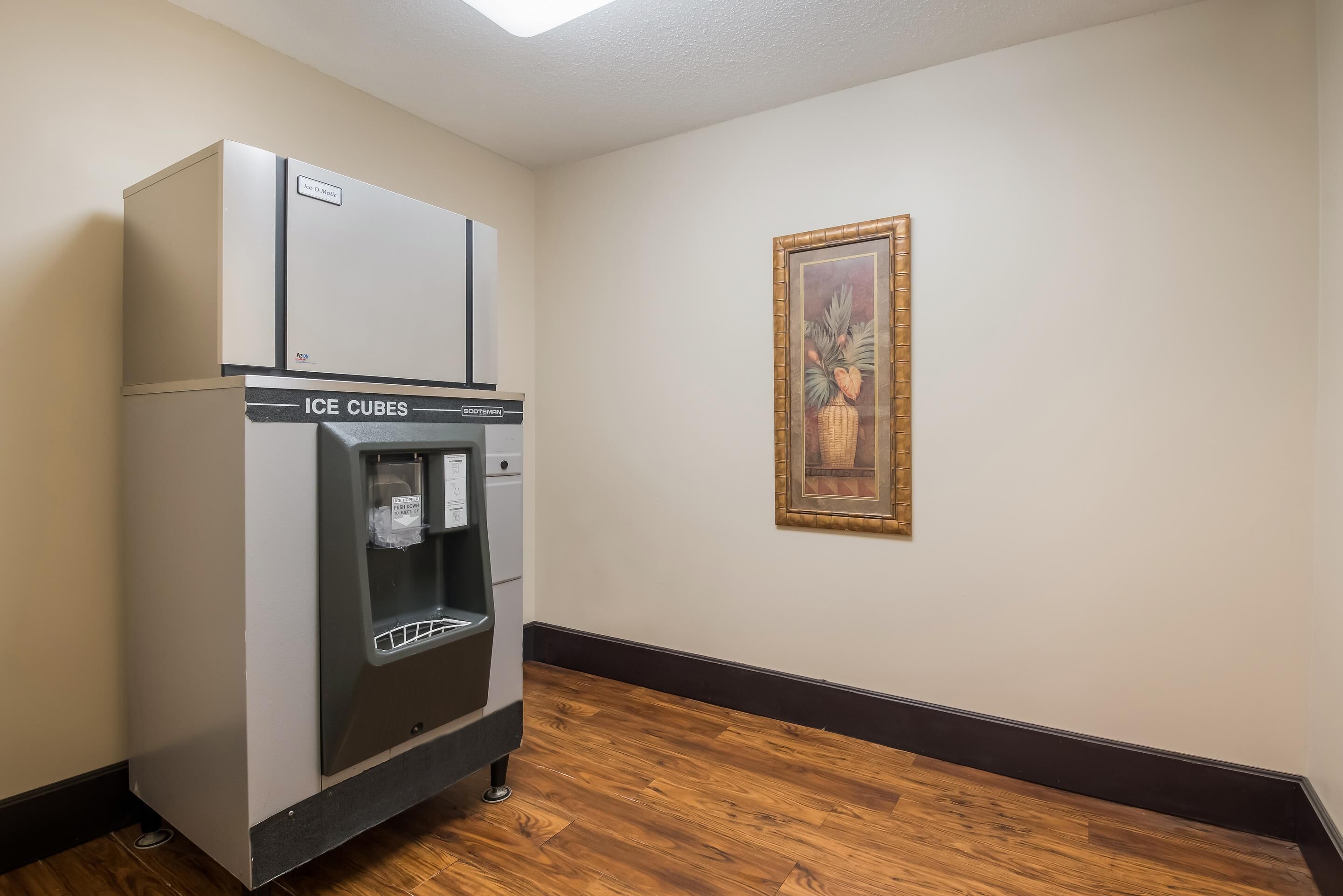A room with a water dispenser and a framed picture on the wall.