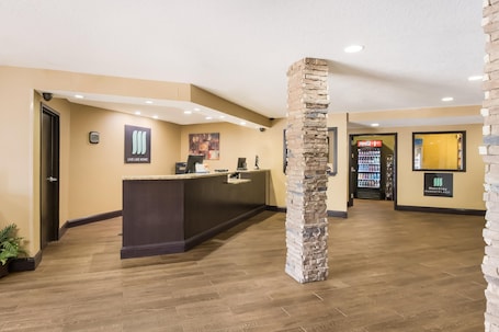 A reception area with a stone pillar, a reception desk, a Coca-Cola refrigerator, and a sign that reads "Live Like Home."