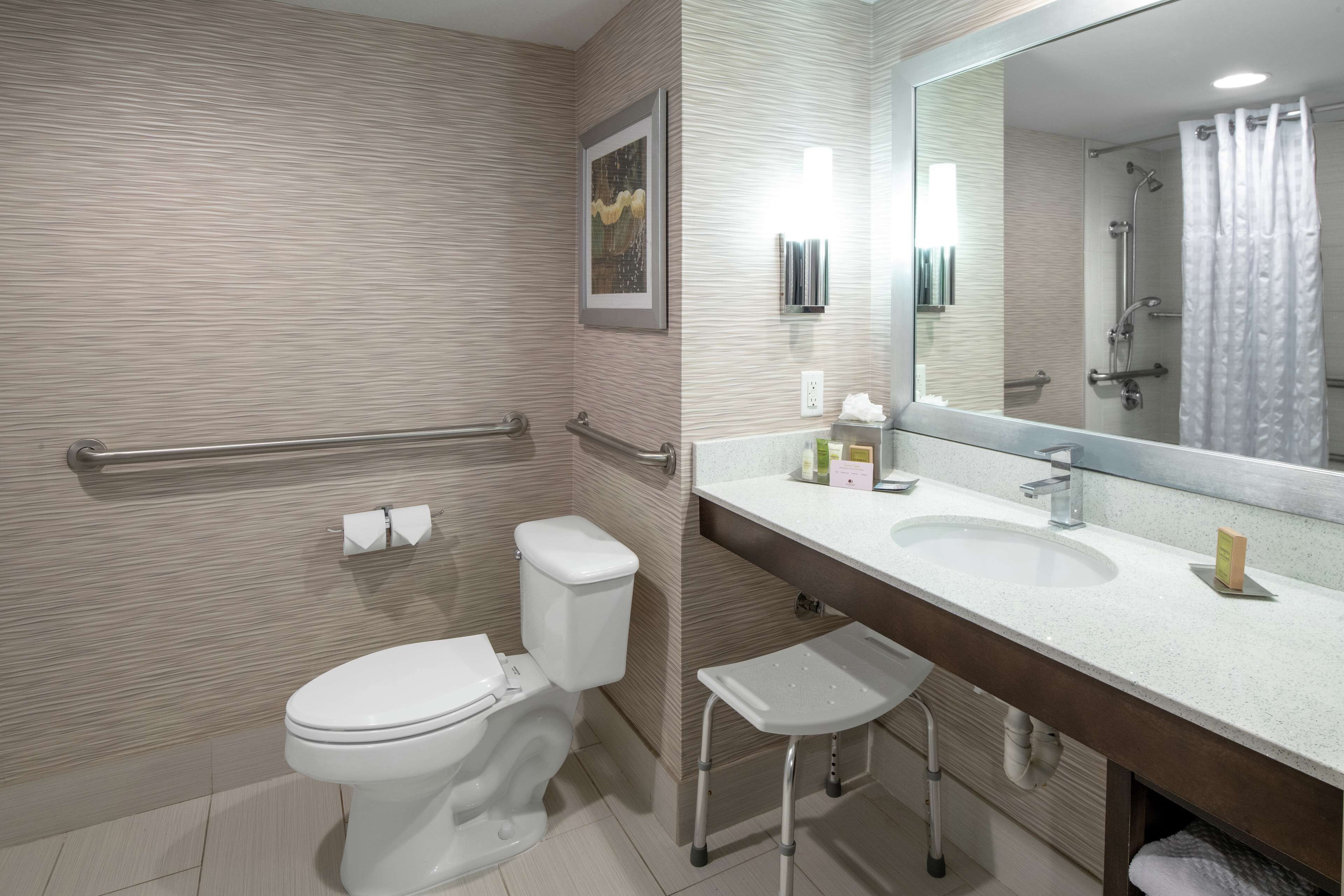 Un baño moderno con inodoro, bidé, tocador con espejo y zona de ducha.