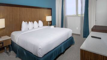 A hotel room with a large bed, two bedside tables, a desk, and a window with curtains.