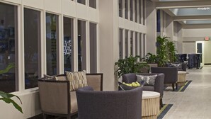 Un vestíbulo amplio con ventanas grandes, asientos modernos y un candelabro decorativo.