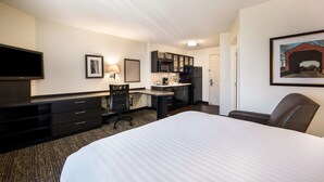 A hotel room with a large bed, a desk with a chair, a kitchenette, and a TV. - Sonesta Simply Suites Detroit Troy (Troy)