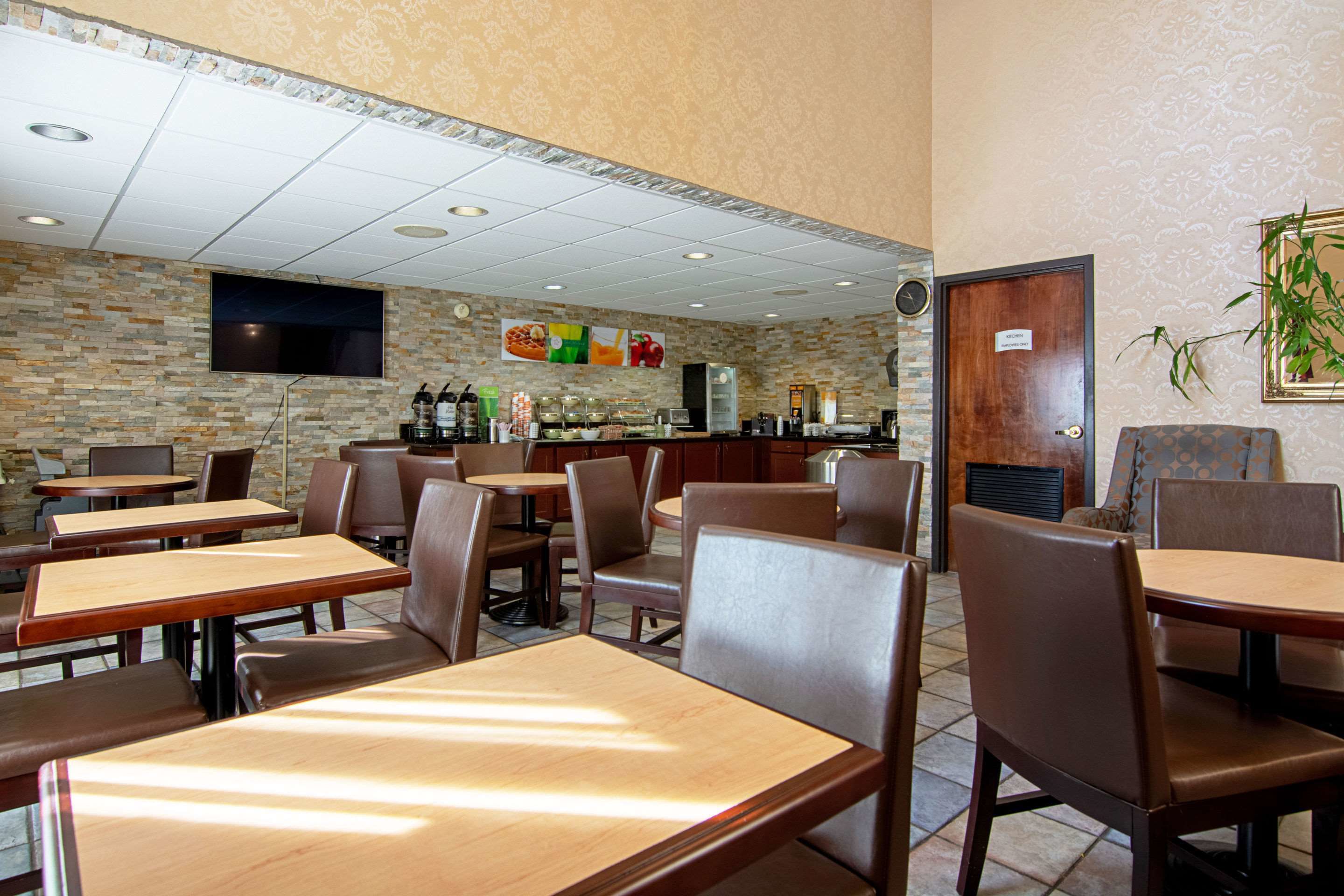 A restaurant interior with booths and tables, a counter with food items, and a television mounted on the wall.
