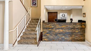A reception area with a stone counter, a sign reading "Quality," and a staircase with patterned carpet.