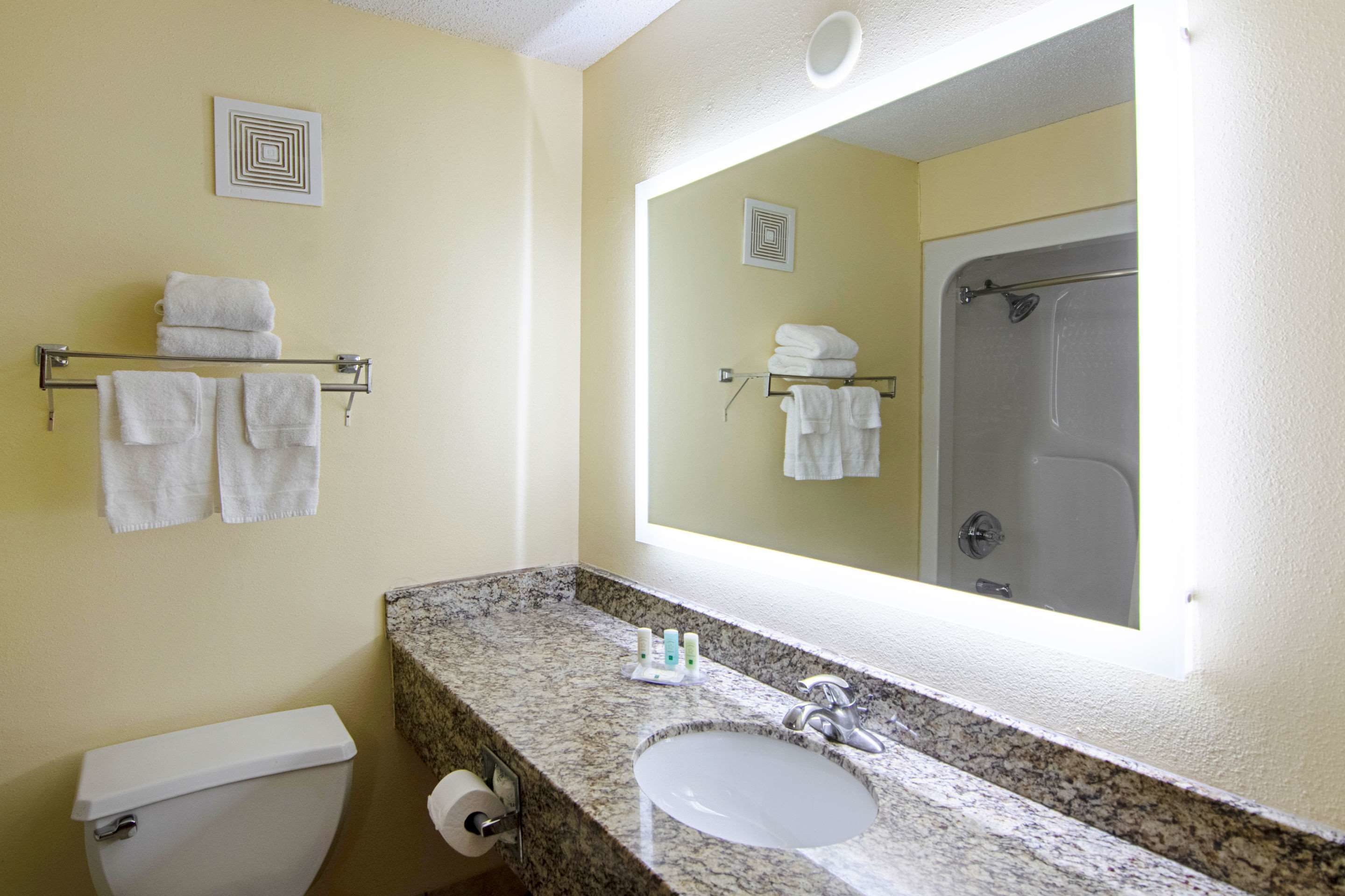 A bathroom with a toilet, sink, and shower. There are towels on a rack and in the shower.