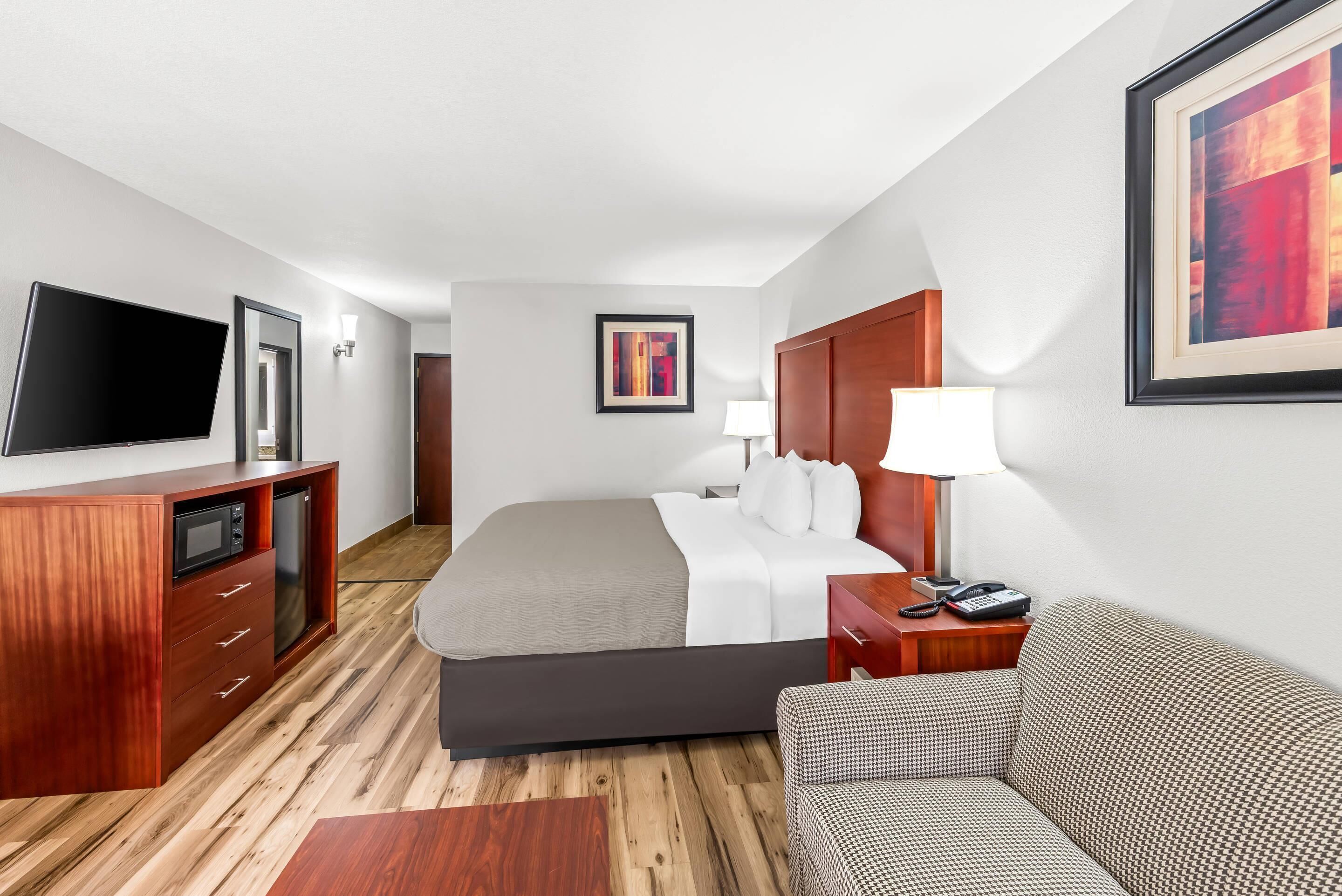 A hotel room with a bed, a TV, a desk, and a sofa.