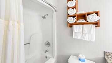 A bathroom with a shower, toilet, and a shelf with towels.