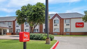 Ein Gebäude der Red Roof Inn & Suites mit gut sichtbarem Eingangsschild, Backsteinfassade und gepflegtem Rasen.